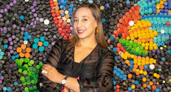 Diana Sabine en la Universidad Ean al frente del mural de tapas plásticas 'Súbete a una movilidad sostenible'